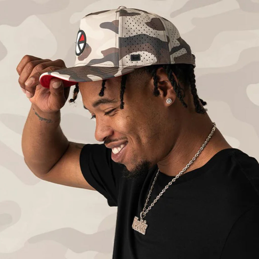 Man wearing the melin x Ethika hat, smiling against a neutral background