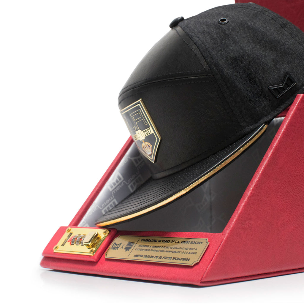 Black LA KINGS x melin cap with gold accents on a red display stand