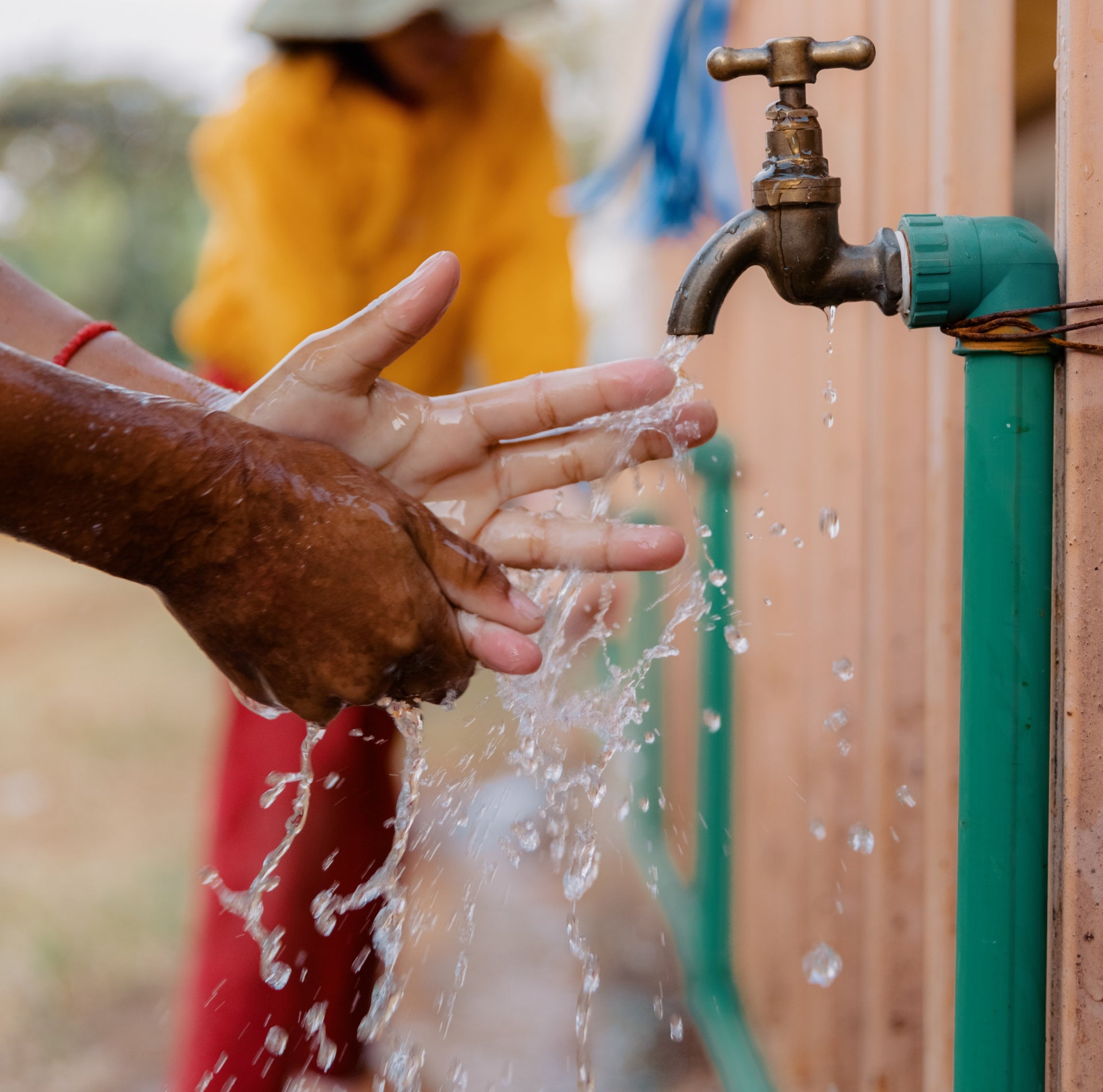 Person washing hands under a running faucet with a blurred background and text about melin Partner Philanthropies