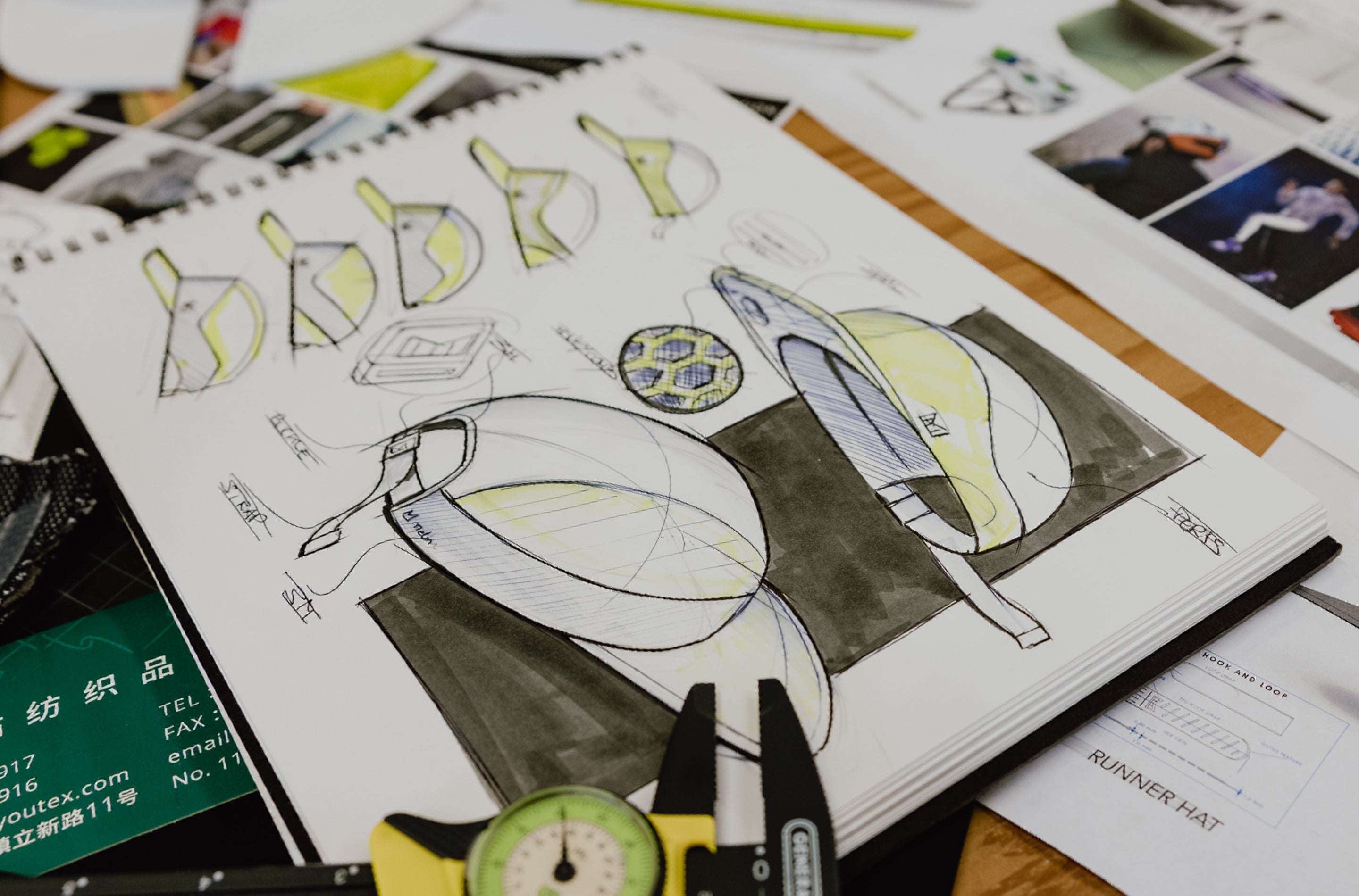 Design sketches of hats in a notebook with measurement tools on a table.