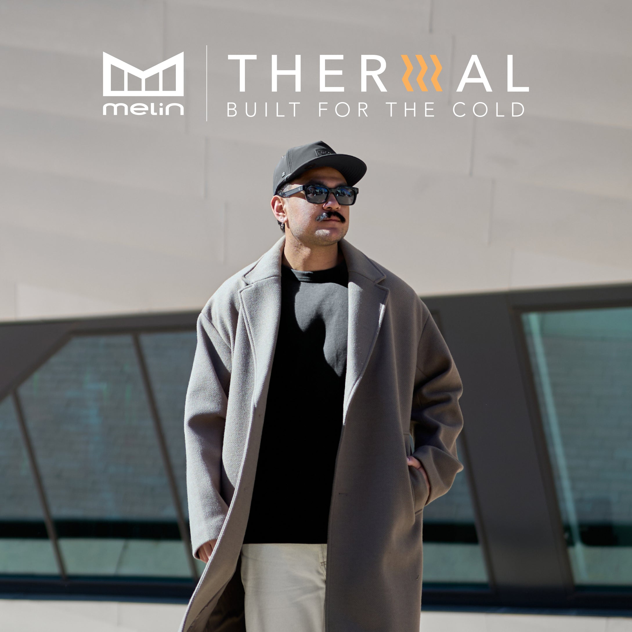 Man wearing a coat and sunglasses with 'melin THERMAL' branding in the background.