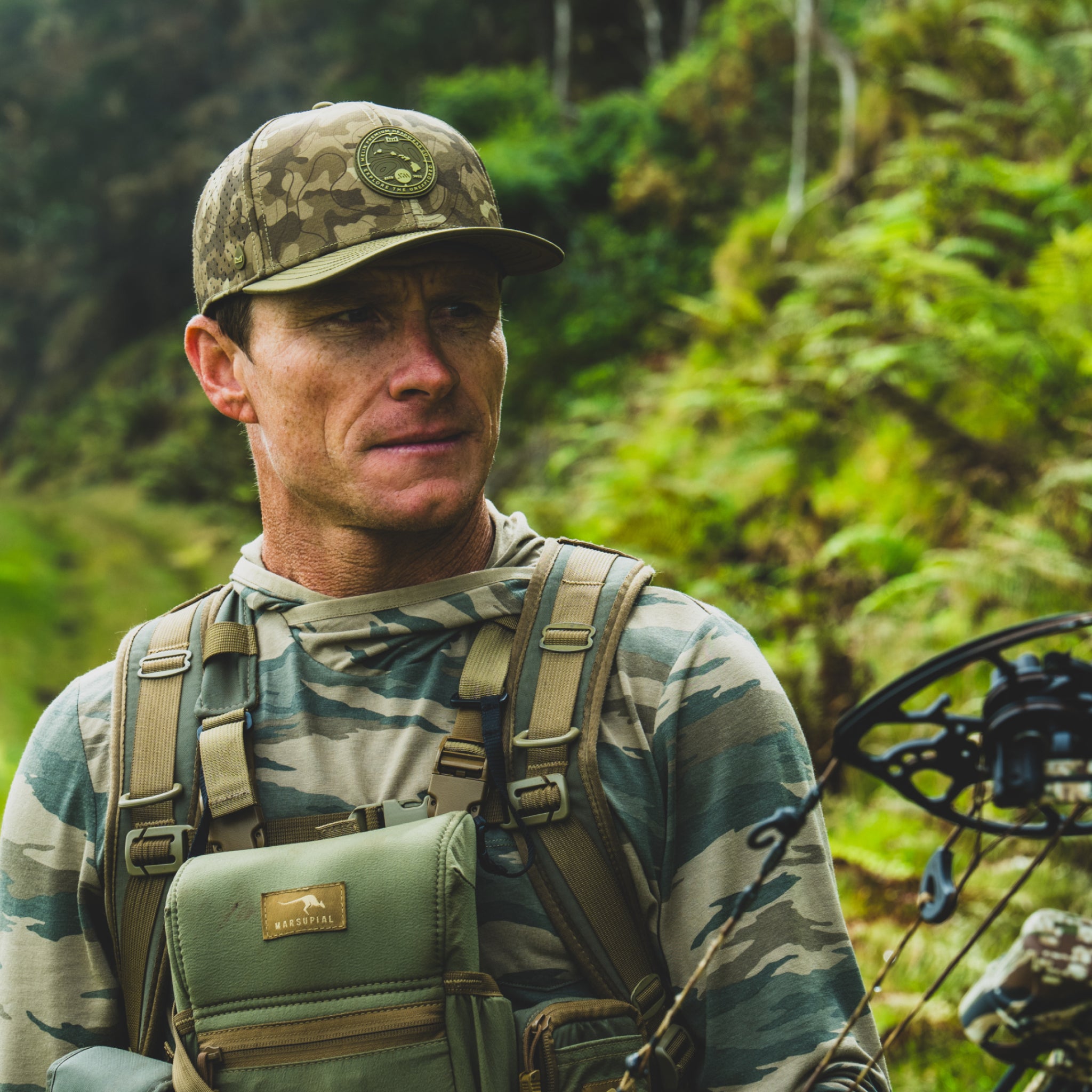 Mark Healey in camouflage gear with a bow in a forest setting