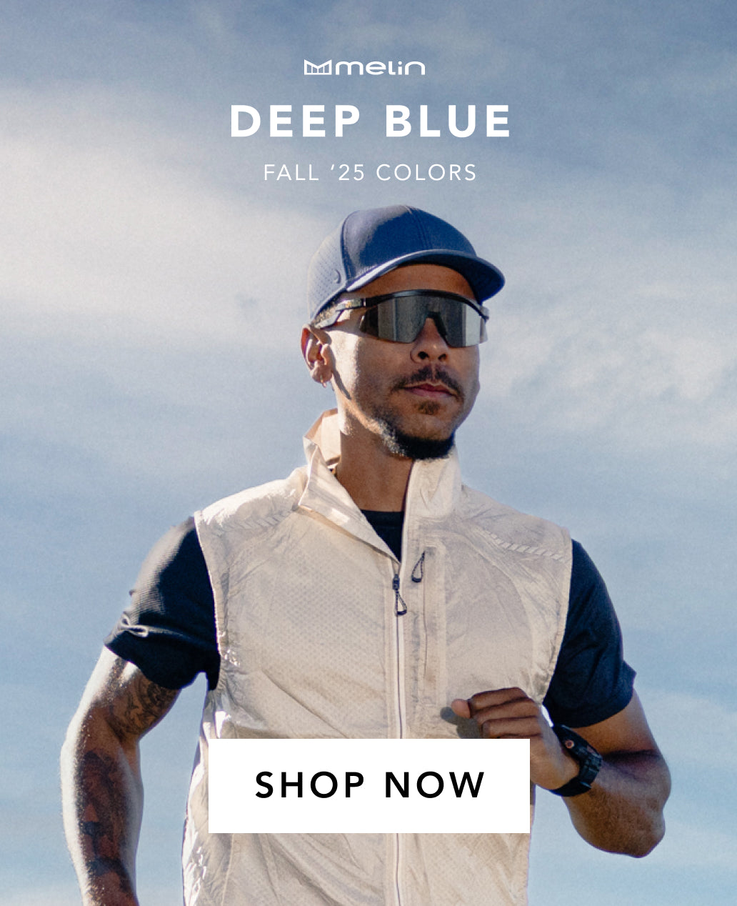 Man wearing a white vest, blue cap, and sunglasses with 'Melin' branding and 'DEEP BLUE FALL '25 COLORS' text.