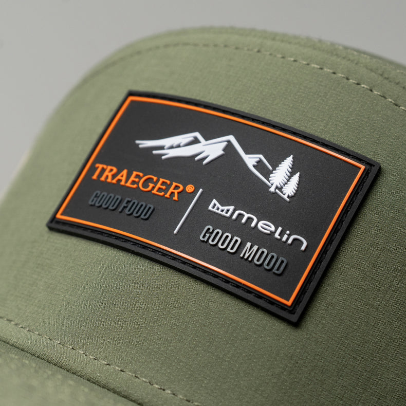 Green jacket with a Traeger and Melin logo patch on a gray background
