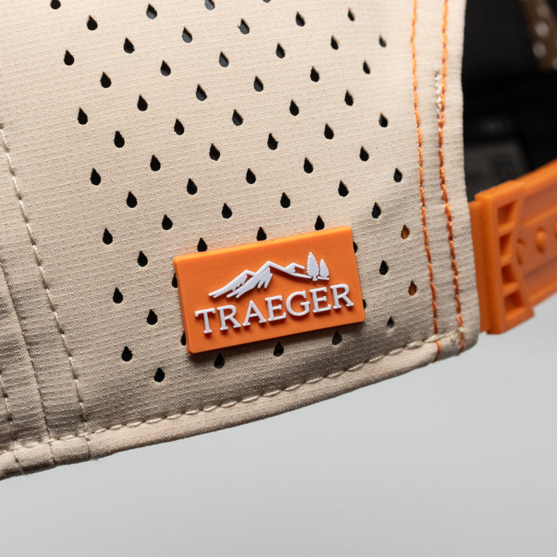Close-up of a Traeger branded melin hat  with a perforated design and orange accent.